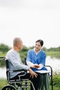 Elderly asian senior man on wheelchair with Asian careful caregiver. Nursing home hospital garden concept are walking in the Royalty Free Stock Photo