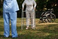 Elderly asian senior woman practice walking with aluminum walker for safety with nurse. Nursing home hospital garden Royalty Free Stock Photo