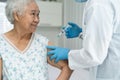 Elderly Asian senior woman wearing face mask getting covid-19 or coronavirus vaccine by doctor make injection Royalty Free Stock Photo