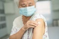 Elderly Asian senior woman wearing face mask getting covid-19 or coronavirus vaccine by doctor make injection Royalty Free Stock Photo