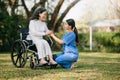 Elderly asian senior woman on wheelchair with Asian careful caregiver. Nursing home hospital garden concept. in sun light Royalty Free Stock Photo