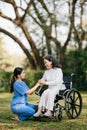 Elderly asian senior woman on wheelchair with Asian careful caregiver. Nursing home hospital garden concept. in sun light Royalty Free Stock Photo