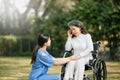 Elderly asian senior woman on wheelchair with Asian careful caregiver. Nursing home hospital garden concept. in sun light Royalty Free Stock Photo