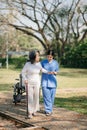 Elderly asian senior woman on wheelchair with Asian careful caregiver. Nursing home hospital garden concept Royalty Free Stock Photo