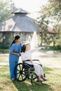 Elderly asian senior woman on wheelchair with Asian careful caregiver. Nursing home hospital garden concept. in sunlight Royalty Free Stock Photo