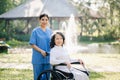 Elderly asian senior woman on wheelchair with Asian careful caregiver. Nursing home hospital garden concept. in sunlight Royalty Free Stock Photo