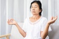 Elderly Asian woman doing yoga and meditating peaceful indoors