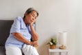 Elderly Asian woman with grey hair sitting lonely on the sofa, Aging society Sad and lonely concept, with copy space for text