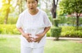 Elderly asian woman having painful stomachache at public park,Senior female suffering from abdominal pain,Close up