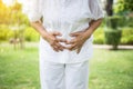 Elderly asian woman having painful stomachache at public park,Senior female suffering from abdominal pain,Close up