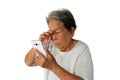 Elderly asian woman are holding and looking mobile phone with poor eyesight isolated on white background Royalty Free Stock Photo