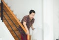 Elderly Asian woman holding sticks while walking down stair at home