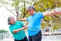 An elderly Asian woman measures the waist circumference of an elderly man with a tape measure. Royalty Free Stock Photo