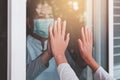 Elderly asian women wearing face mask with hands touching on window to people,Stay at home during coronavirus and covid-19 epidemi