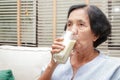 Elderly Asian women drink milk containing calcium to prevent osteoporosis.