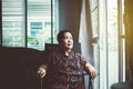 Elderly asian woman looking out the window at house,Senior having sorrowful and depressed