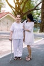 Elderly Asian woman walking to do physical with stick at park,Daughter take care and support,Elderly social asia concept