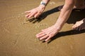 Elderly attractive woman touching the water on the seashore Royalty Free Stock Photo