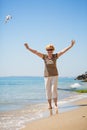 Elderly attractive woman walking along the beach and showing her palm hands Royalty Free Stock Photo