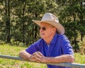 Elderly Australian farmer, looking over a fence into a paddock