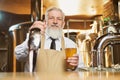 Elderly barman standing at bar counter with beer glass. Royalty Free Stock Photo