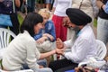 An elderly bearded Indian in a black turban gives a woman an acupressure of the hand