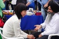 An elderly bearded Indian in a black turban gives a woman an acupressure of the hand