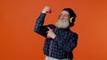 Elderly bearded man listening music via headphones, working out, lifting pink dumbbells, healthcare