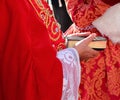 elderly bishop with red cassock and the ancient bible with the sacred scriptures in his hand during the religious rite