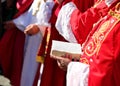 elderly bishop with red cassock and Bible in hand during the religious rite