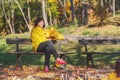 Elderly brown hair woman sitting on bench in autumn park