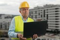 Elderly builder man with focused expression looking at laptop