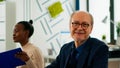 Elderly businessman looking at camera smiling sitting in brainstorming room Royalty Free Stock Photo