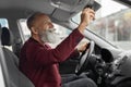 Elderly businessman in setting rearview mirror in car