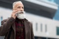 Elderly businessman walking by city, having phone call Royalty Free Stock Photo