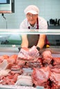 Elderly butcher shop seller laying out raw pork ribs in display case Royalty Free Stock Photo