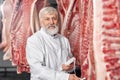 Worker posing in refrigerator near pork carcasses. Royalty Free Stock Photo