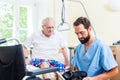 Elderly care nurse helping senior from bed to wheel chair Royalty Free Stock Photo