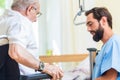 Elderly care nurse helping senior from bed to wheel chair