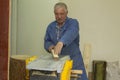 An elderly carpenter handles the bar on the machine. men`s work with tools.