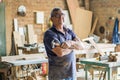 Elderly carpenter posing with crossed arms in his workshop.