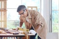 Elderly carpenter wearing safety glasses, working at wooden desk with different craft tools, enjoying his DIY hobby, senior Royalty Free Stock Photo