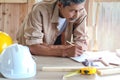 Elderly carpenter working at wooden desk with different craft tools, enjoying his DIY hobby, senior craftsman drawing a design of Royalty Free Stock Photo