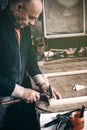 An elderly carpenter works in his workshop.