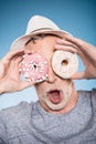 Elderly casual man holding donuts in front of eyes