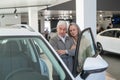 An elderly Caucasian couple chooses a new car at a car dealership.