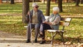 Elderly Caucasian couple sitting on the bench looking at each other in a park woman holds her husbands& x27; hands Royalty Free Stock Photo