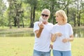 Elderly caucasian couple who wearing white shirt and sun glasses holding pure water bottle in the park and discussion with his Royalty Free Stock Photo
