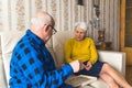 Elderly caucasian heterosexual couple on leather sofa solving jigsaw puzzle in their vintage apartment. Active seniors. Royalty Free Stock Photo