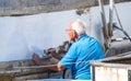 Elderly Caucasian man painting a boat on a sunny day Royalty Free Stock Photo